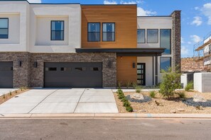 A modern two-story house with a garage, a stone facade, and a landscaped front yard. - Red Rock Isle 7 Bedroom Townhouse (Washington)
