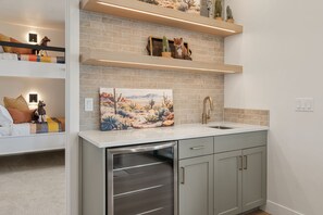 Cozinha moderna com forno embutido, pia e um quadro decorativo sobre o balcão.
