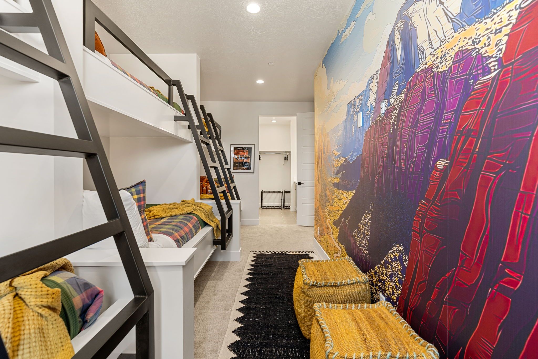 A modern interior with a staircase, a large mural, and a bed with colorful bedding.