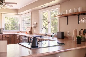 Una cocina moderna con una isla central, ventanas amplias y un ventilador de techo.