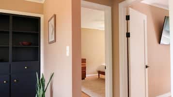 A hallway with a dark-colored cabinet, a potted plant, and a door leading to another room.