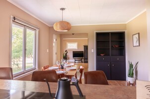 Un comedor con una mesa dispuesta para cuatro personas, una cafetera y un televisor al fondo.