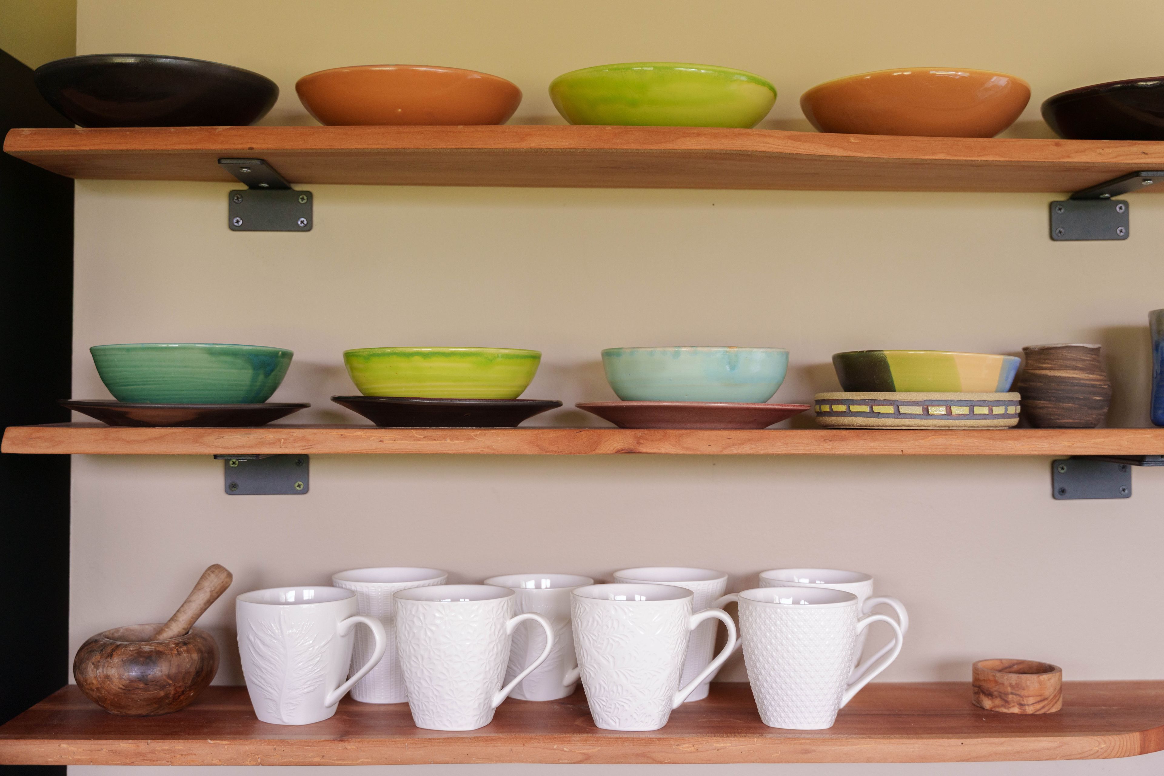 Une étagère avec plusieurs bols en céramique et des tasses blanches.