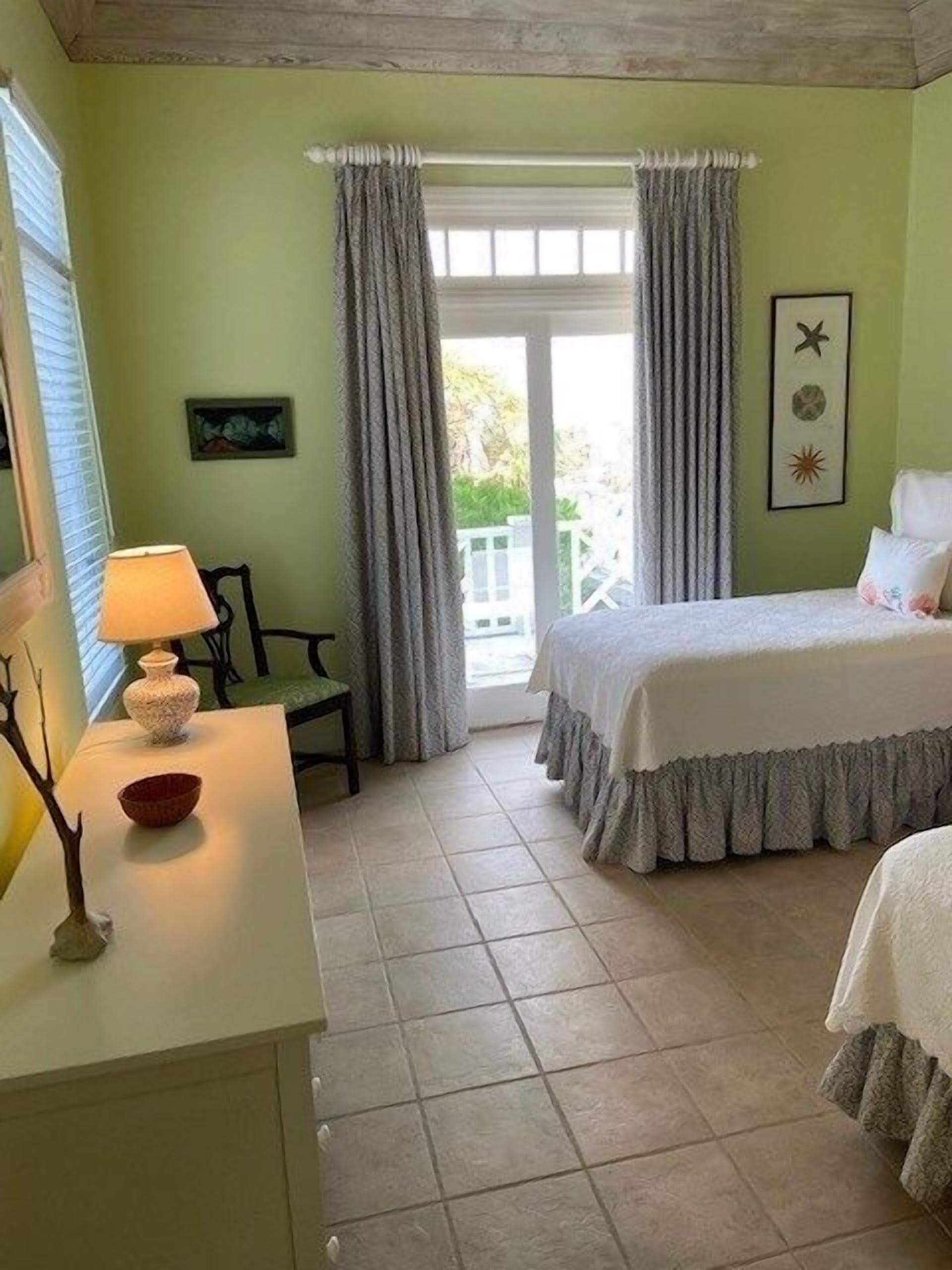 A room with a bed, a desk, a chair, and a window with curtains.
