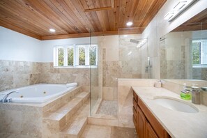 A modern bathroom with a freestanding bathtub, a glass-enclosed shower, and a vanity with a large mirror.