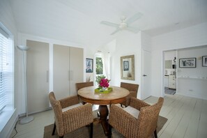 Uma área de refeições com mesa redonda, cadeiras de vime e um ventilador de teto.