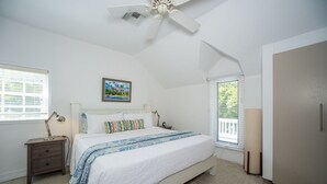 Ein Schlafzimmer mit einem Bett, Nachttischen, einem Deckenventilator, einem Fenster mit Jalousien und einer Tür.