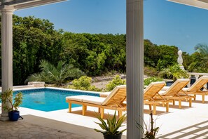 A pool area with lounge chairs, a clear blue pool, and a backdrop of dense greenery. - High Life - Private Hilltop Estate With Pool And Panoramic Ocean 4 Bedroom Home (Governor's Harbour)