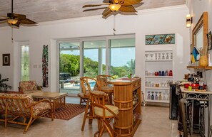 Um quarto espaçoso com área de jantar, bar e vista para uma piscina.