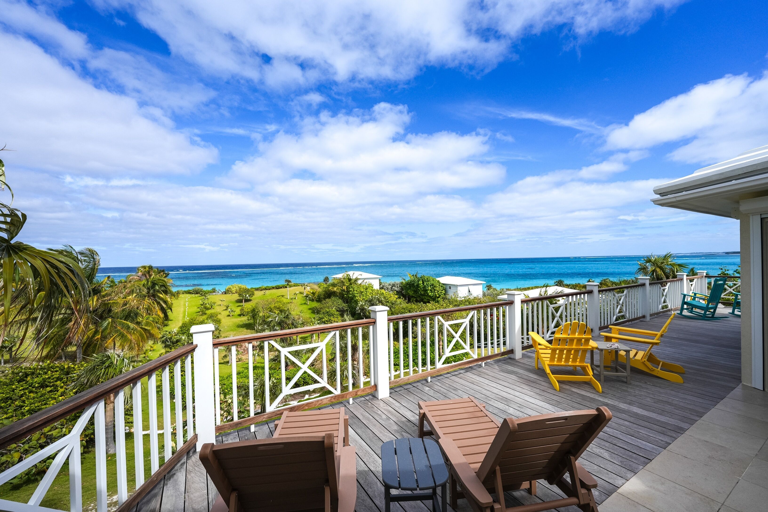 A wooden deck with outdoor furniture overlooking a coastal view.