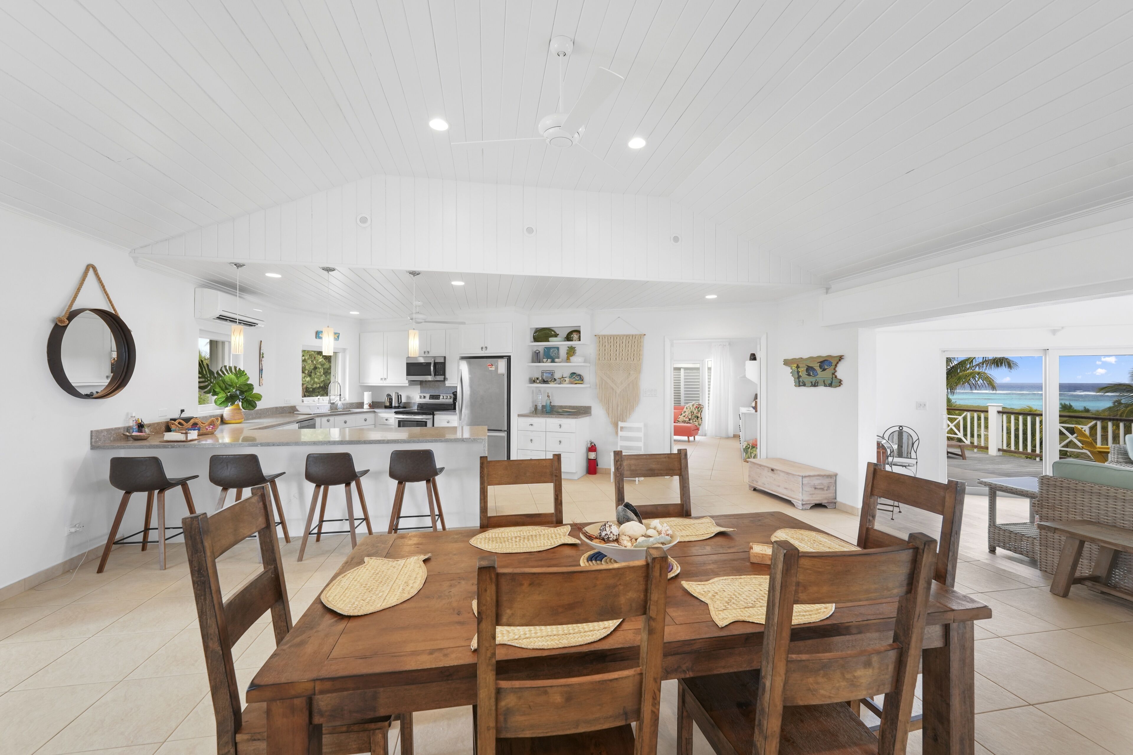 Une cuisine spacieuse avec des meubles blancs, un îlot central et un coin repas comprenant une table et des chaises en bois.