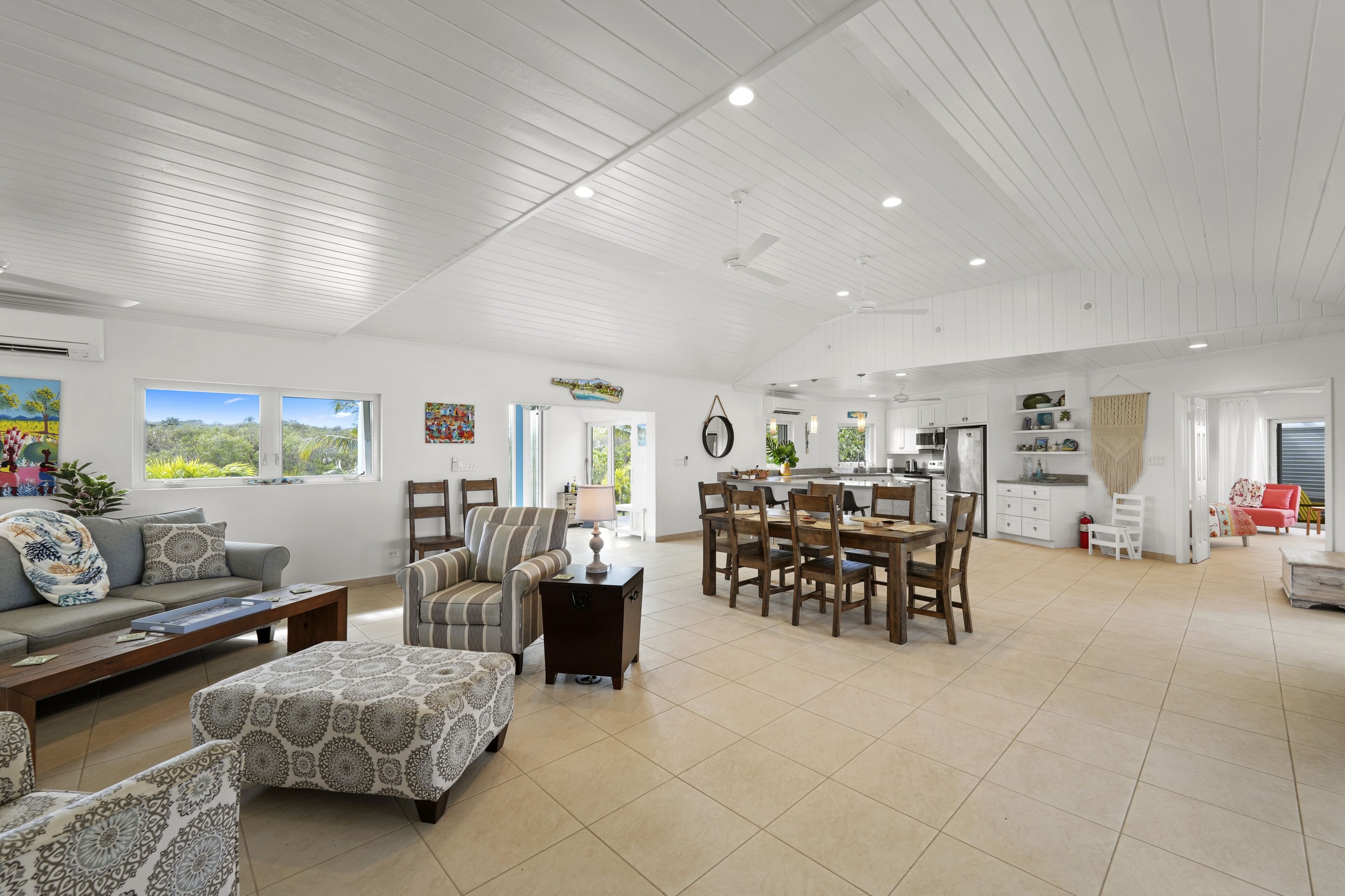 A spacious living area with a dining table, sofas, and a kitchen in the background.
