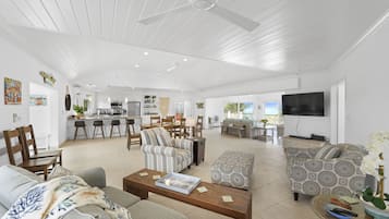 Ampla sala de estar com cozinha, área de refeições e espaço de estar com sofás e mesa de centro.