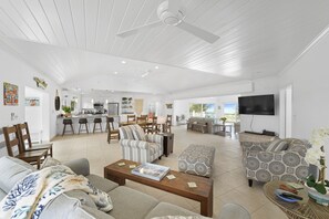 A spacious living area with a kitchen, dining space, and a seating area with sofas and a coffee table. - Outer Reef - Newly Remodeled Beachfront House, Walk Rest/bar 2 Bedroom Home (Governor's Harbour)