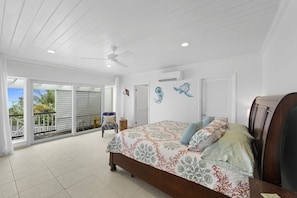 A bedroom with a large bed, a ceiling fan, and a view to a balcony. - Outer Reef - Newly Remodeled Beachfront House, Walk Rest/bar 2 Bedroom Home (Governor's Harbour)