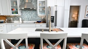 A modern kitchen with white cabinets, a stainless steel range hood, and a built-in water dispenser. - Leisure Beach Ocean Retreat - Luxury Beachfront House 3 Bedroom Home (Current)
