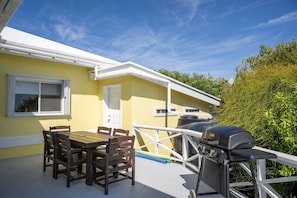Une terrasse avec une table et des chaises, un barbecue et une fenêtre donnant sur un espace verdoyant.