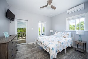 Ein Schlafzimmer mit Bett, Nachttisch, Kommode, Deckenventilator und Klimaanlage.