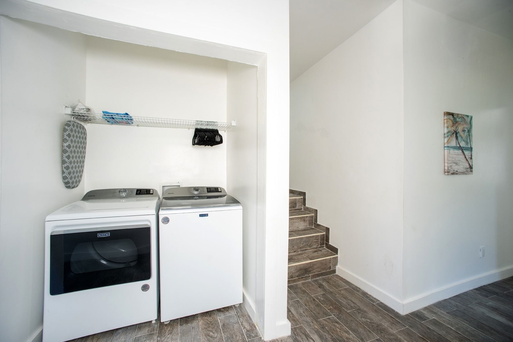 A laundry area with two front-loading washing machines and a drying rack.
