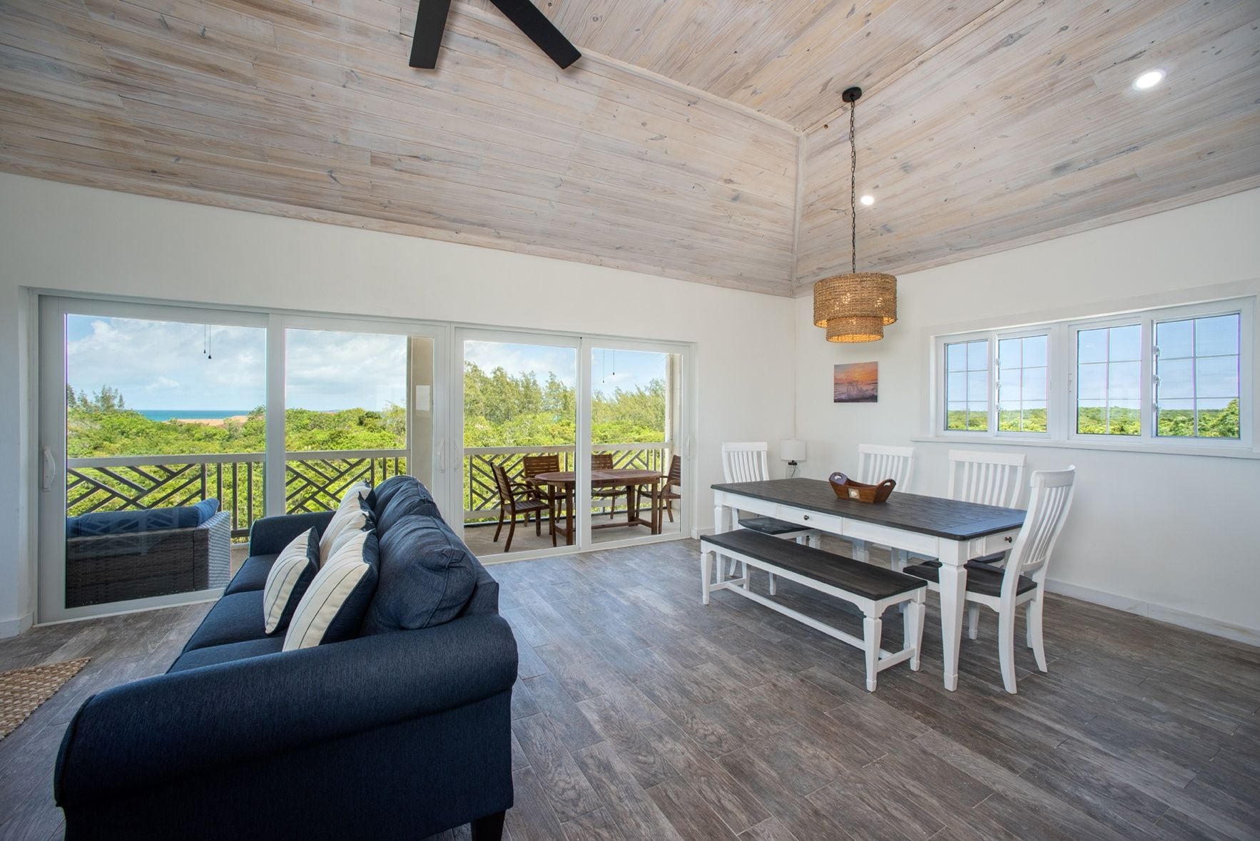 A spacious room with a large sliding glass door leading to an outdoor area, a dining table with chairs, and a sofa.