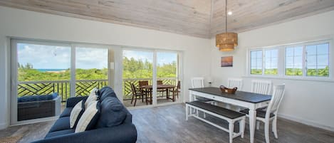 A spacious room with a large sliding glass door leading to an outdoor area, a dining table with chairs, and a sofa.