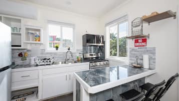 A modern kitchen with white cabinetry, a central island, stainless steel appliances, and a 'NO SMOKING' sign.