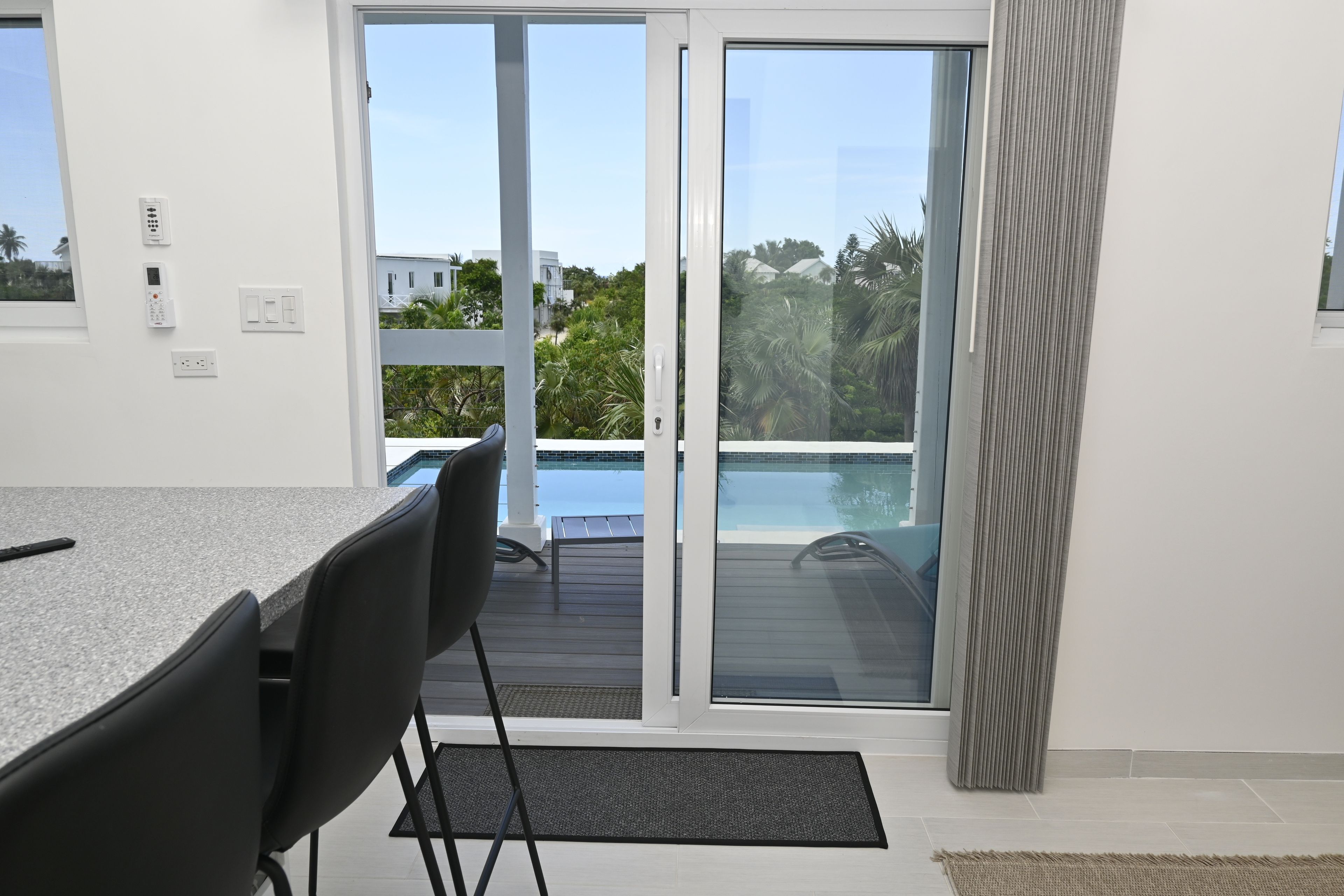 Eine moderne Küche mit Essbereich, einem Pool und einer Schiebetür zu einer Terrasse.