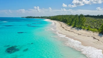 A beach with clear turquoise waters and a sandy shore.