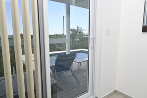 A room with a sliding glass door leading to an outdoor area with a pool and a chair. - Sapphire Cottage - Brand New Beach Villa With Pool 2 Bedroom Home (North Palmetto Point)
