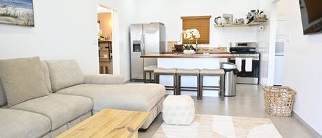 Een moderne woonkamer met een bank, een houten salontafel en een vloerkleed.