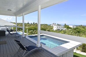 A pool area with lounge chairs, a view of the ocean, and surrounding greenery. - Sapphire Cottage - Brand New Beach Villa With Pool 2 Bedroom Home (North Palmetto Point)