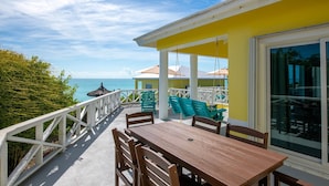 Ein Holztisch mit Stühlen auf einem Balkon mit Blick auf das Meer.