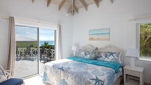 Ein Schlafzimmer mit einem Bett, einem Nachttisch, einem Fenster und Meerblick.