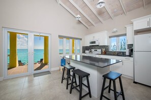 A modern kitchen with a large island, white cabinets, and a view of the ocean. - Tranquilville - Newly Remodeled Estate, Calm Caribbean W/pool 4 Bedroom Home (Current)