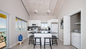 A modern kitchen with a central island, white cabinetry, and a view to the outside.