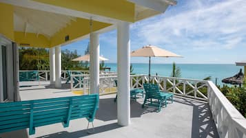 A covered outdoor seating area with chairs and a bench, overlooking a body of water.