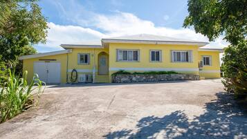 A yellow building with a garage, a stone wall, and a paved driveway.