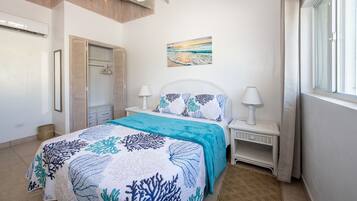 A bedroom with a bed, bedside tables, a ceiling fan, a painting, and a window.