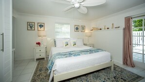 Quarto com cama, mesas de cabeceira, ventilador de teto e janela com persianas.