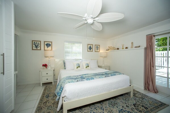 A bedroom with a bed, nightstands, a ceiling fan, and a window with blinds.