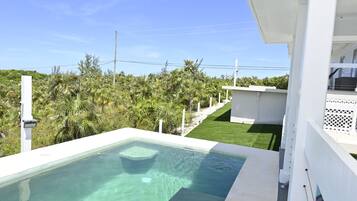 A swimming pool with clear water, surrounded by lush greenery and a white building structure.