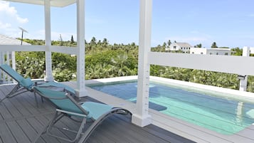 A poolside area with two lounge chairs and a pool.