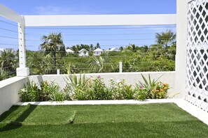 A fenced outdoor area with artificial grass, surrounded by a white wall and a lattice fence. - Emerald Cottage - Brand New Beach Cottage With Pool, Walk To La 1 Bedroom Home (North Palmetto Point)