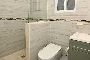 A bathroom with a shower, toilet, and sink. - Emerald Cottage - Brand New Beach Cottage With Pool, Walk To La 1 Bedroom Home (North Palmetto Point)