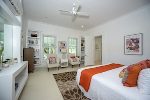 A bedroom with a bed, two chairs, a bookshelf, a wardrobe, and a ceiling fan. - Buena Vista Estate - Historic Estate Private Pool, Golf Cart 6 Bedroom Home (Governor's Harbour)