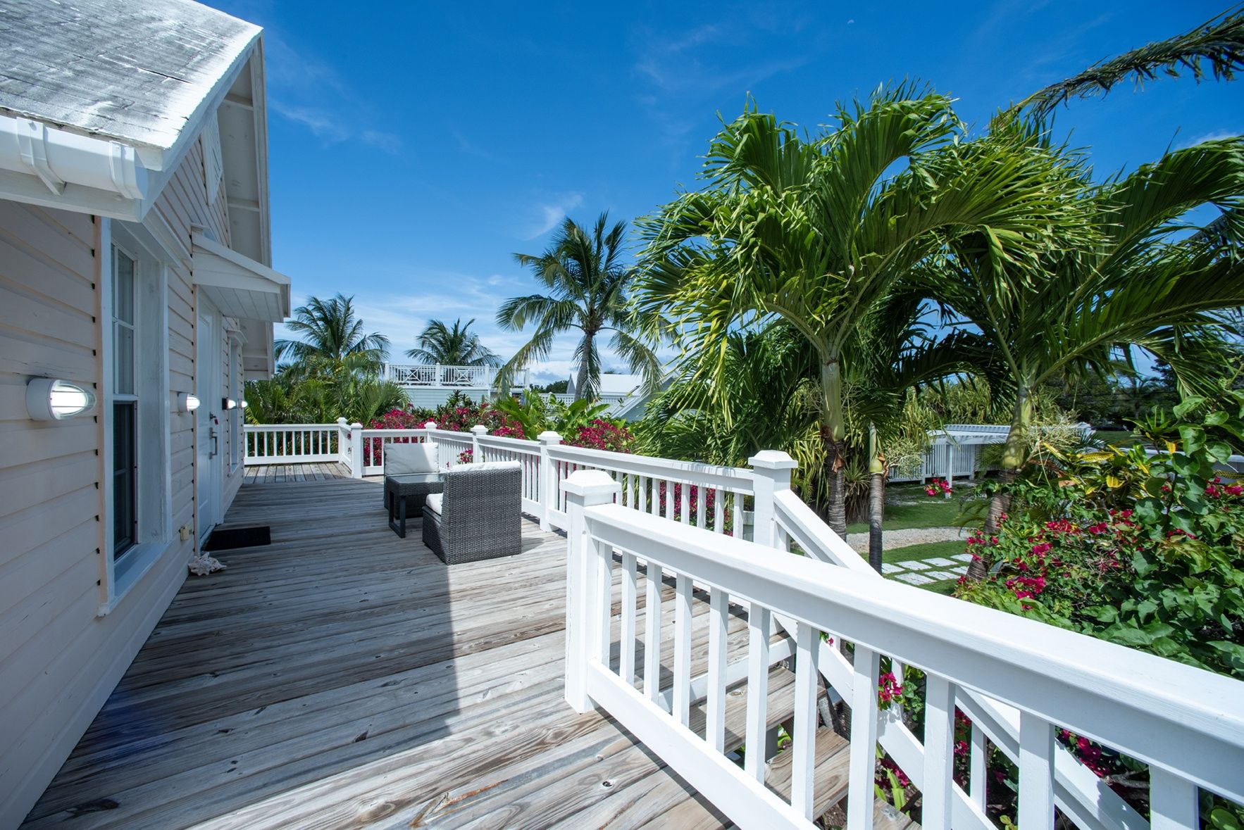 A wooden deck with a white railing, a wicker chair, and a small table.