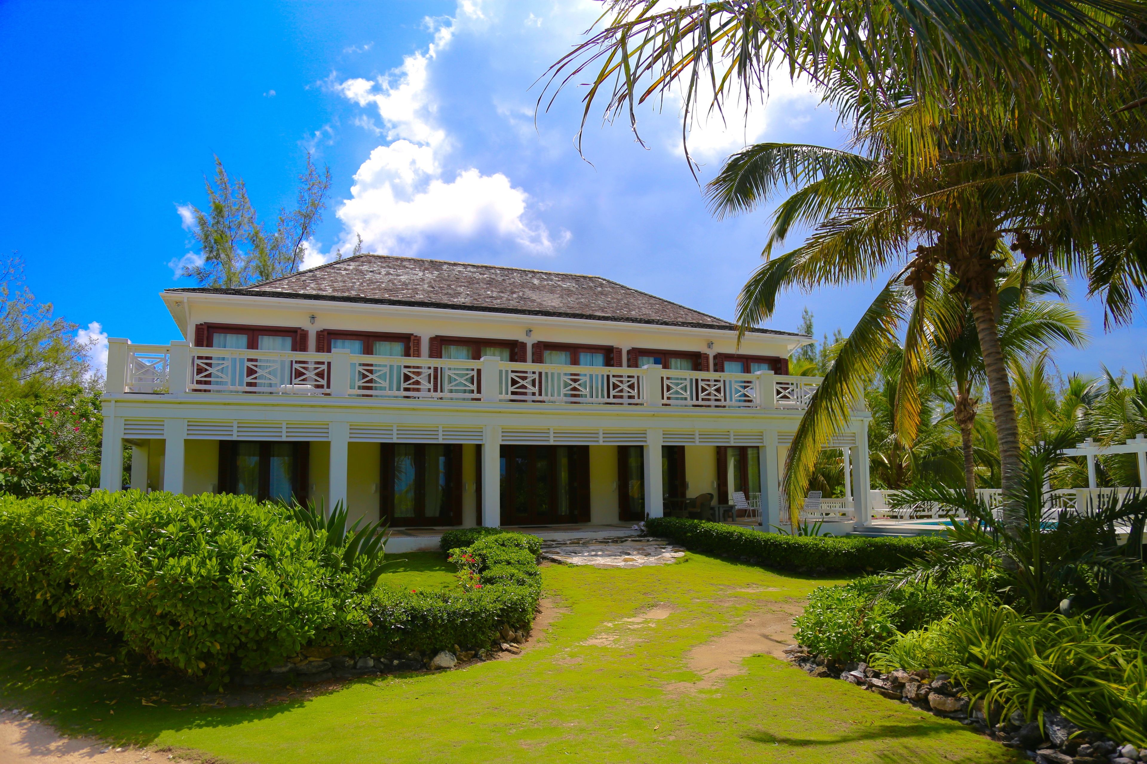 A two-story building with a balcony, surrounded by lush greenery and palm trees.