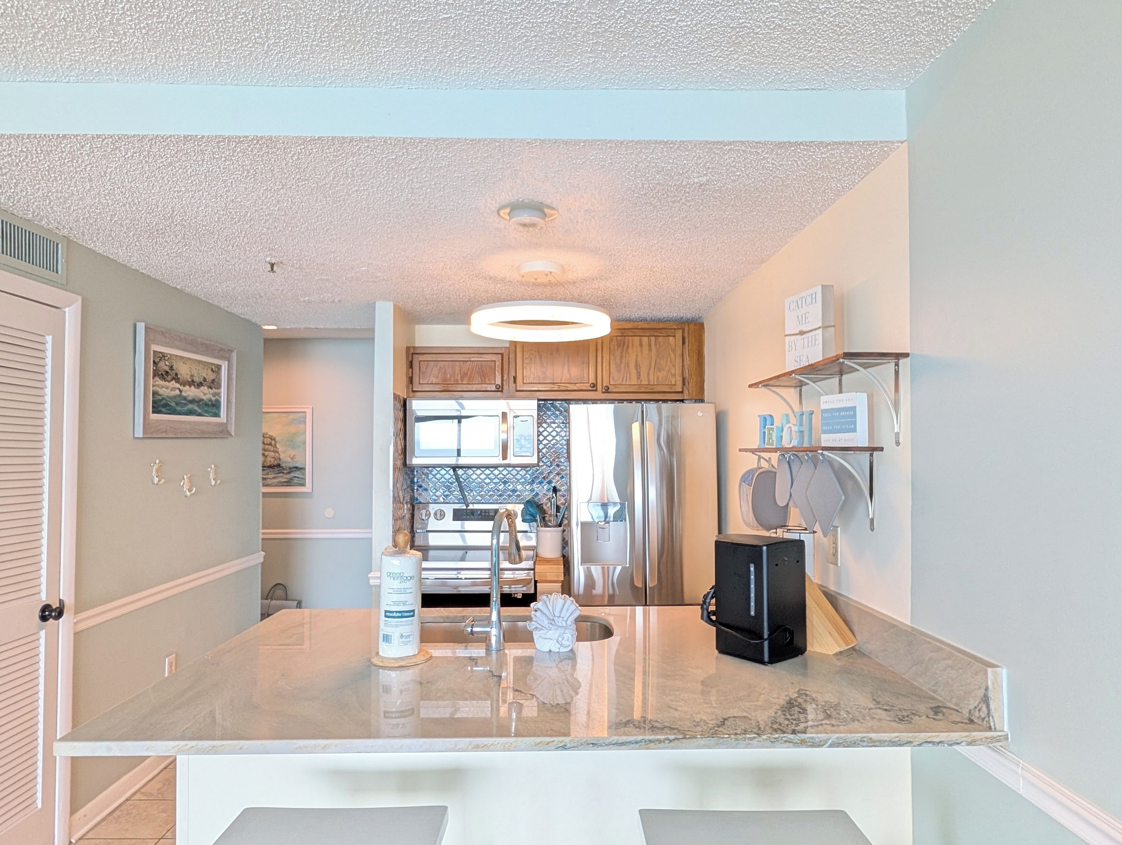 Una cocina con una isla central, armarios de madera, microondas y refrigerador.