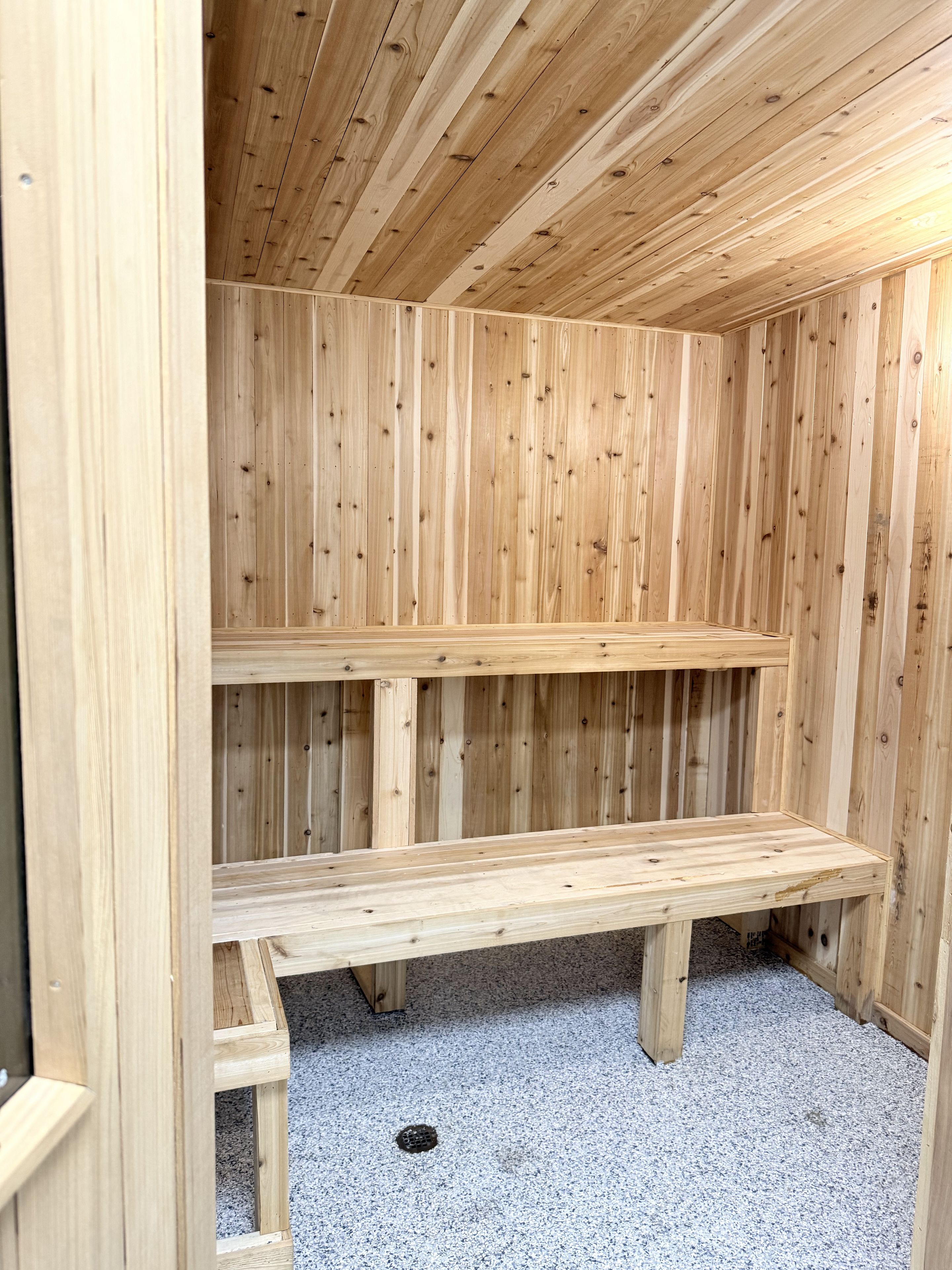 A wooden sauna with benches and a sloped ceiling.