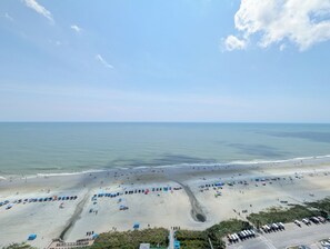 A beach with umbrellas, a parking lot, and a clear sky. - Ocean Front 2 BR | Myrtle Beach Resort - RT1902 (Myrtle Beach)